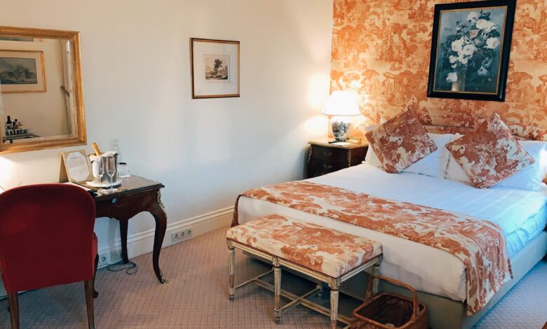 Belle chambre parentale dotée d'un magnifique papier peint orange qui se marie avec la couleur des coussins et des draps du lit