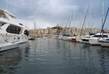 Vue panoramique du Vieux-Port de Marseille avec yachts de luxe amarrés et immeubles résidentiels de standing en arrière-plan, illustrant la fusion entre tradition maritime et modernité digitale dans le secteur immobilier marseillais.